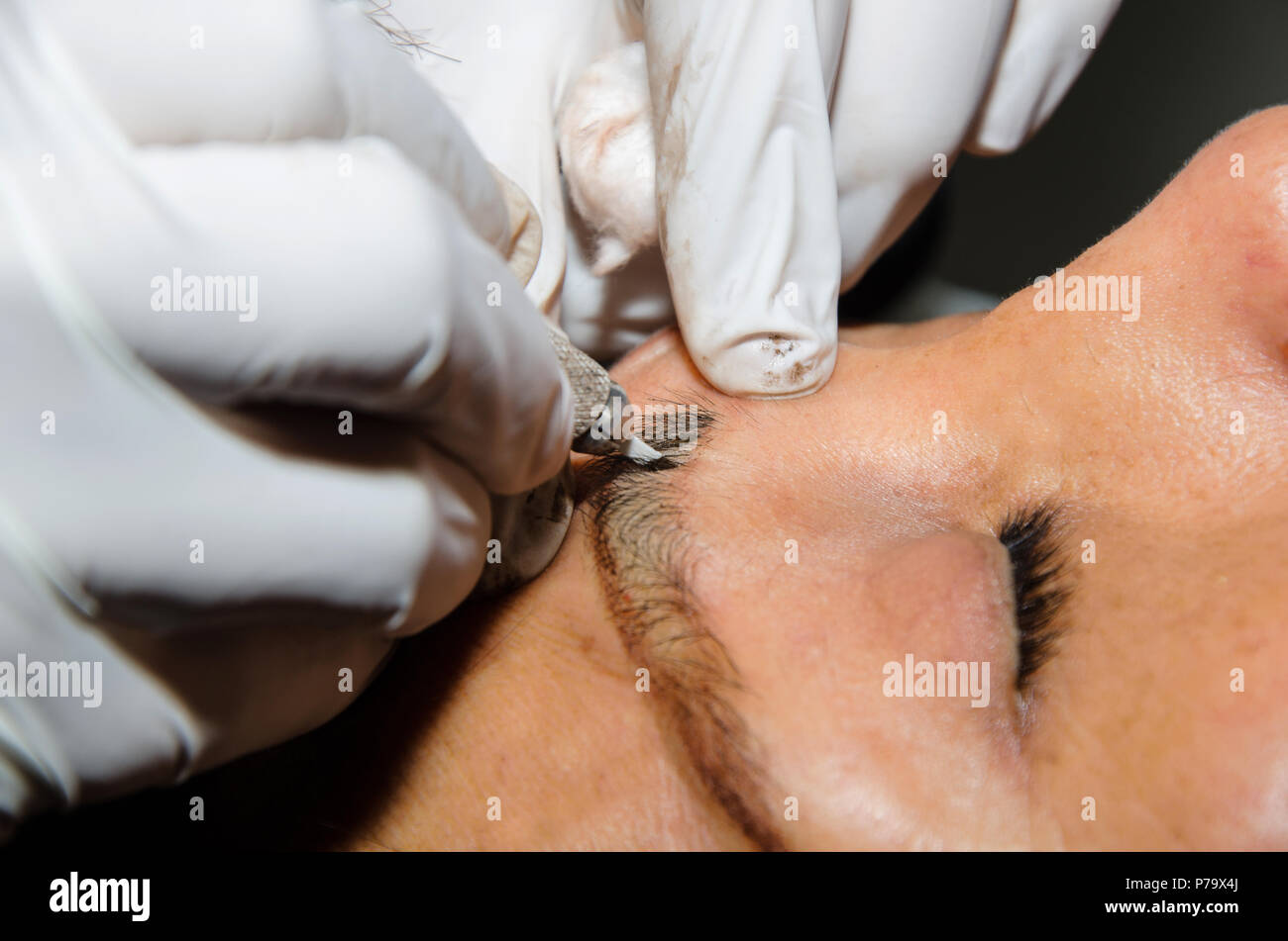 Permanent makeup tattooing of eyebrows. Cosmetologist applying permanent make up on eyebrows - eyebrow tattoo Stock Photo