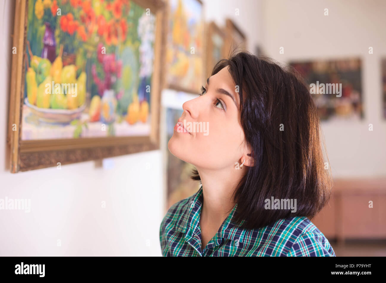 Young woman looking at painting in art gallery. Stock Photo