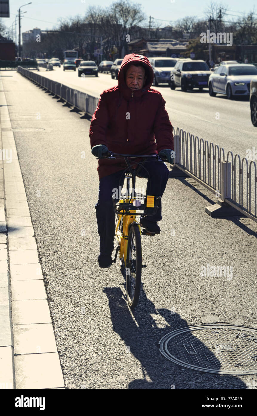 Chinese man rides a yellow rental bicycle in Beijing Stock Photo