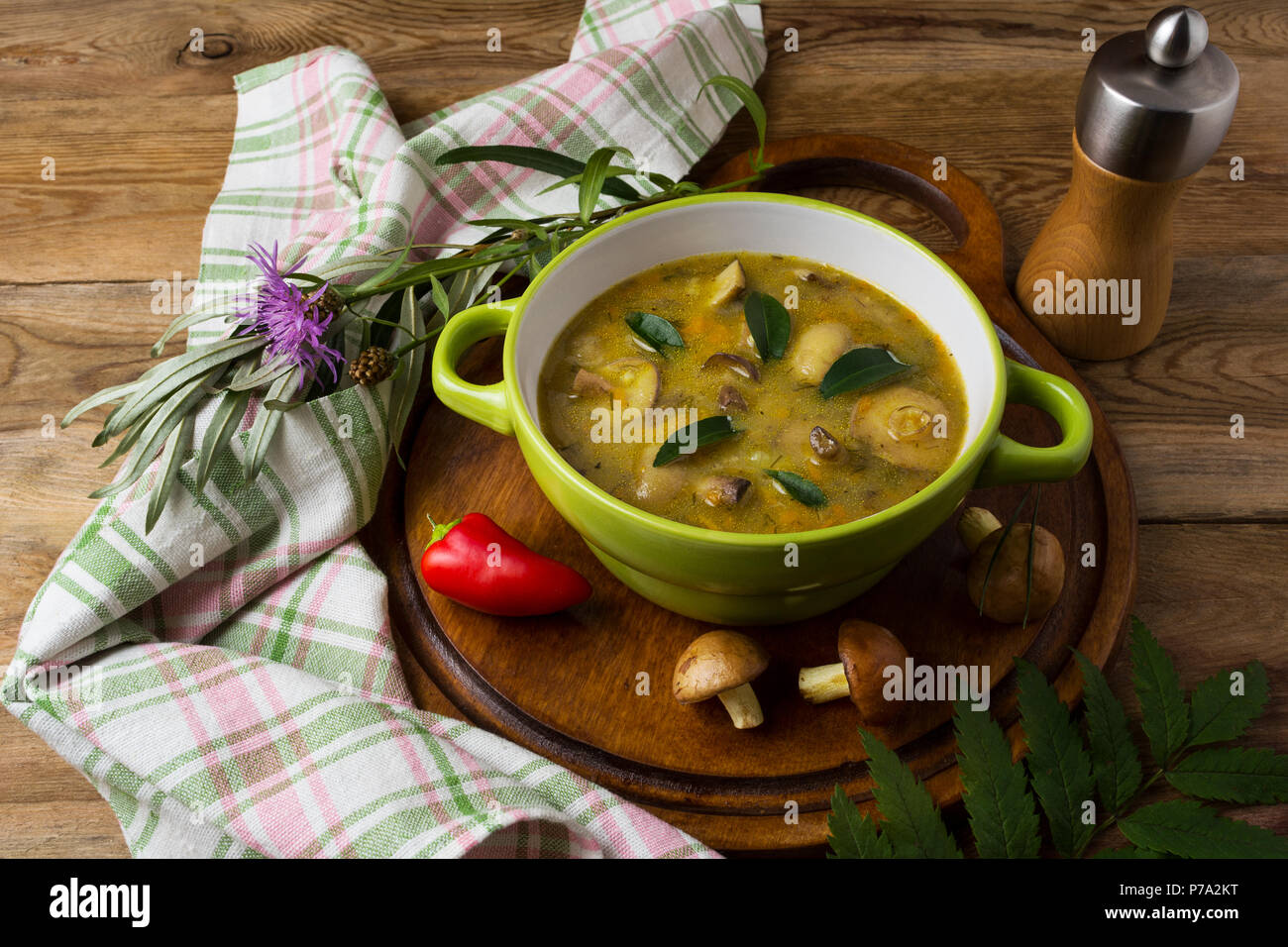 Mushroom homemade soup in the green rustic plate and pepper mill on the wooden table. Vegetarian healthy food Stock Photo