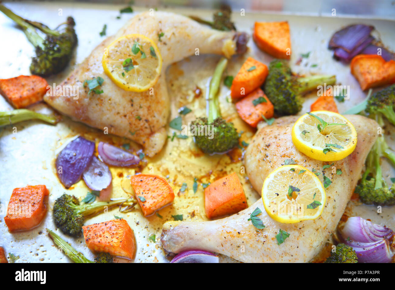 Overhead of chicken quarters with broccoli, sweet potatoes, onion and lemon Stock Photo