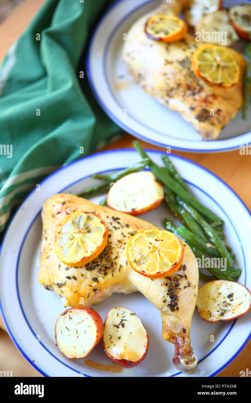 Chicken quarters with green beans and potatoes on blue and white plates from overhead Stock Photo
