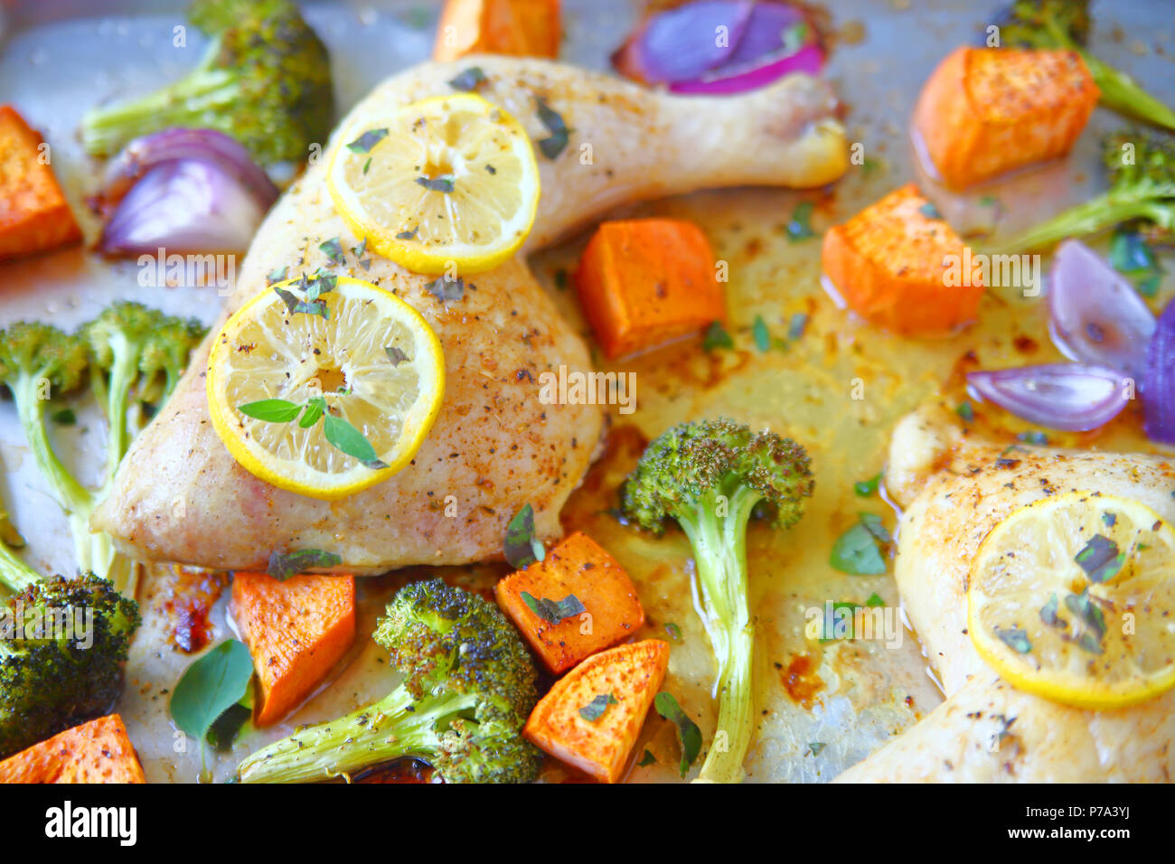 Overhead of chicken quarters with lemon, sweet potatoes, broccoli and onions Stock Photo