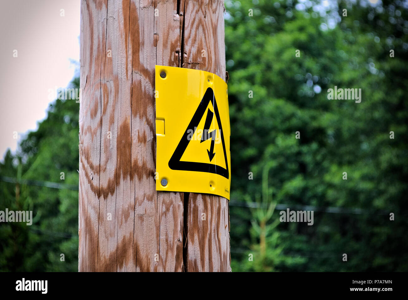 Electrical sign on a wooden post with blurry background. Stock Photo