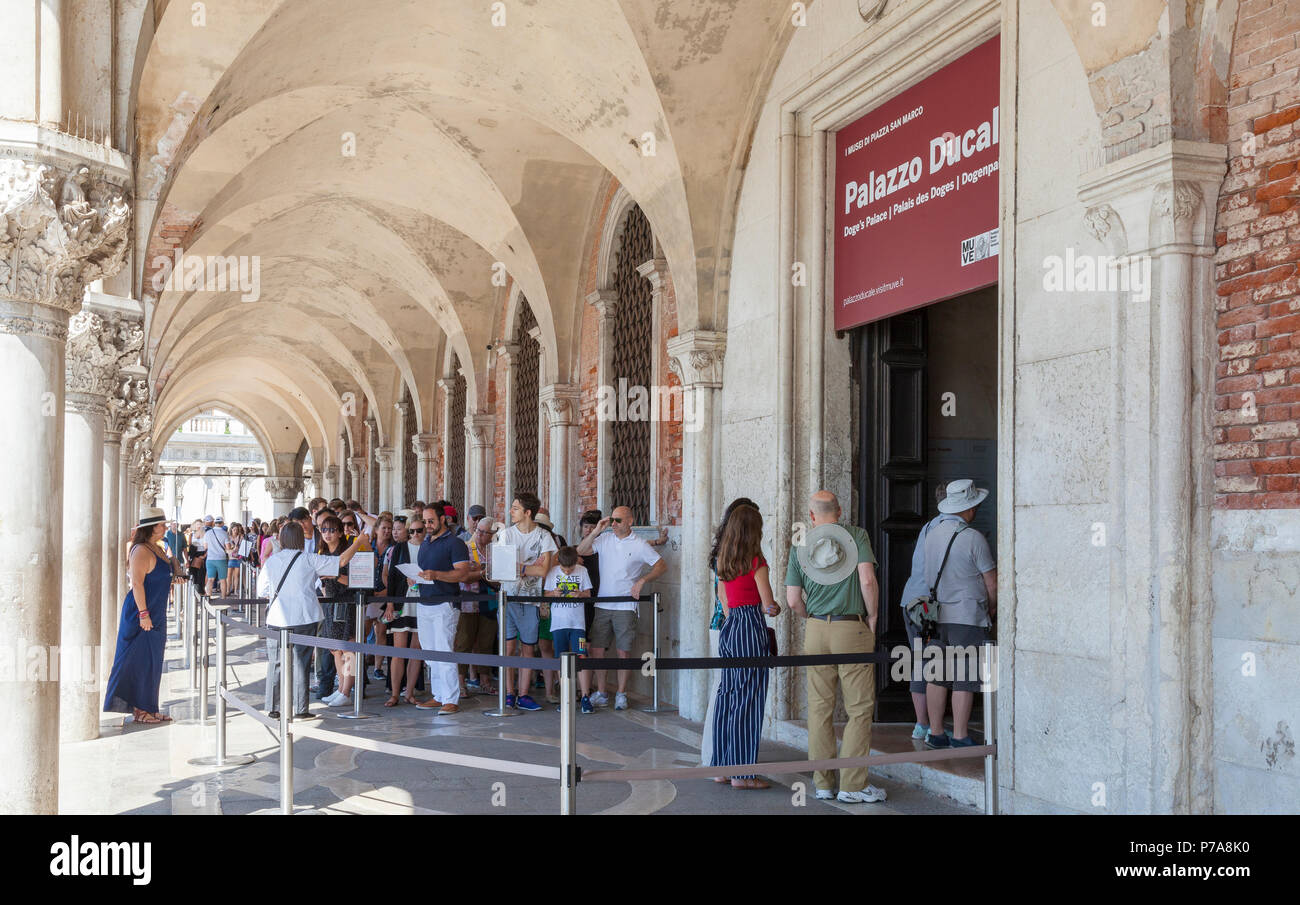 Long queue of tourists waiting to enter the Doges Palace, Palazzo Ducale, Ducal Palace in San Marco, Venice, Veneto, Italy queueing under the arcade o Stock Photo