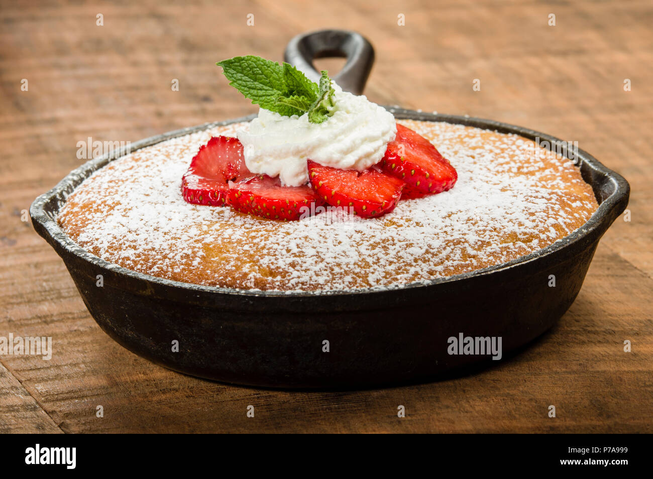 Skillet baked yellow cake with cream and red strawberries Stock Photo