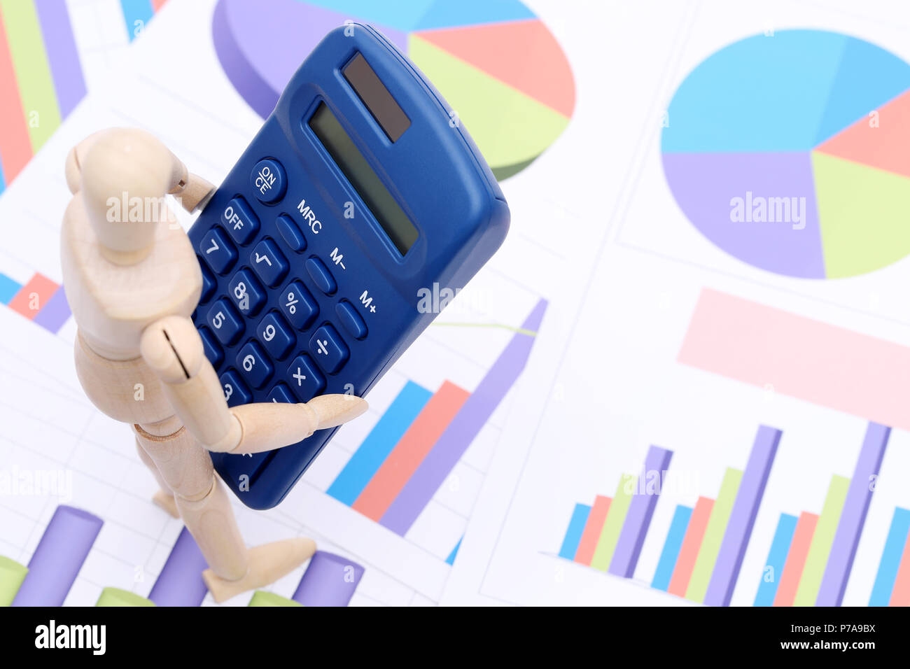 Wooden dummy with calculator on color chart printed documents ...