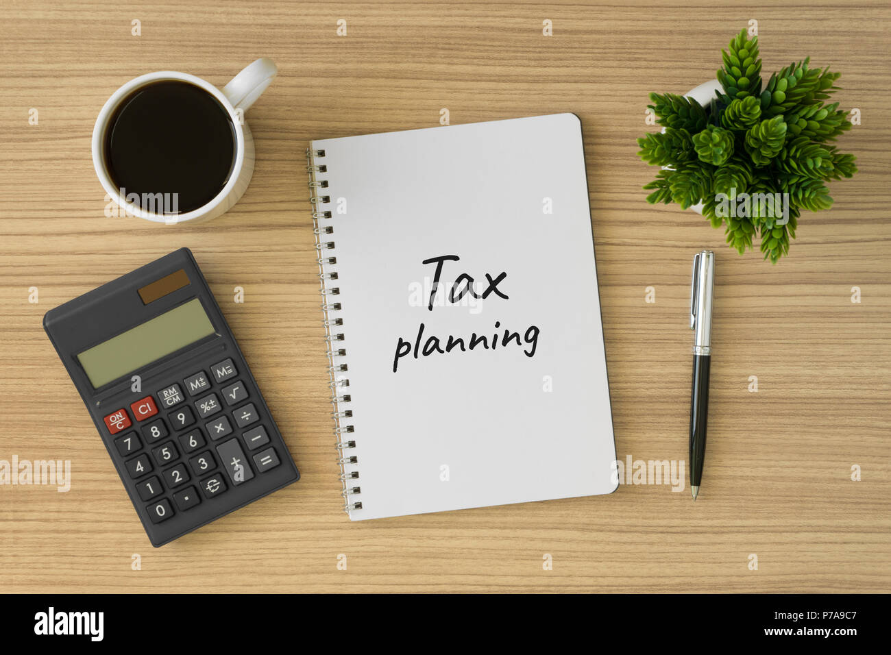 Tax planning written on notebook. Top view of wood desk with office