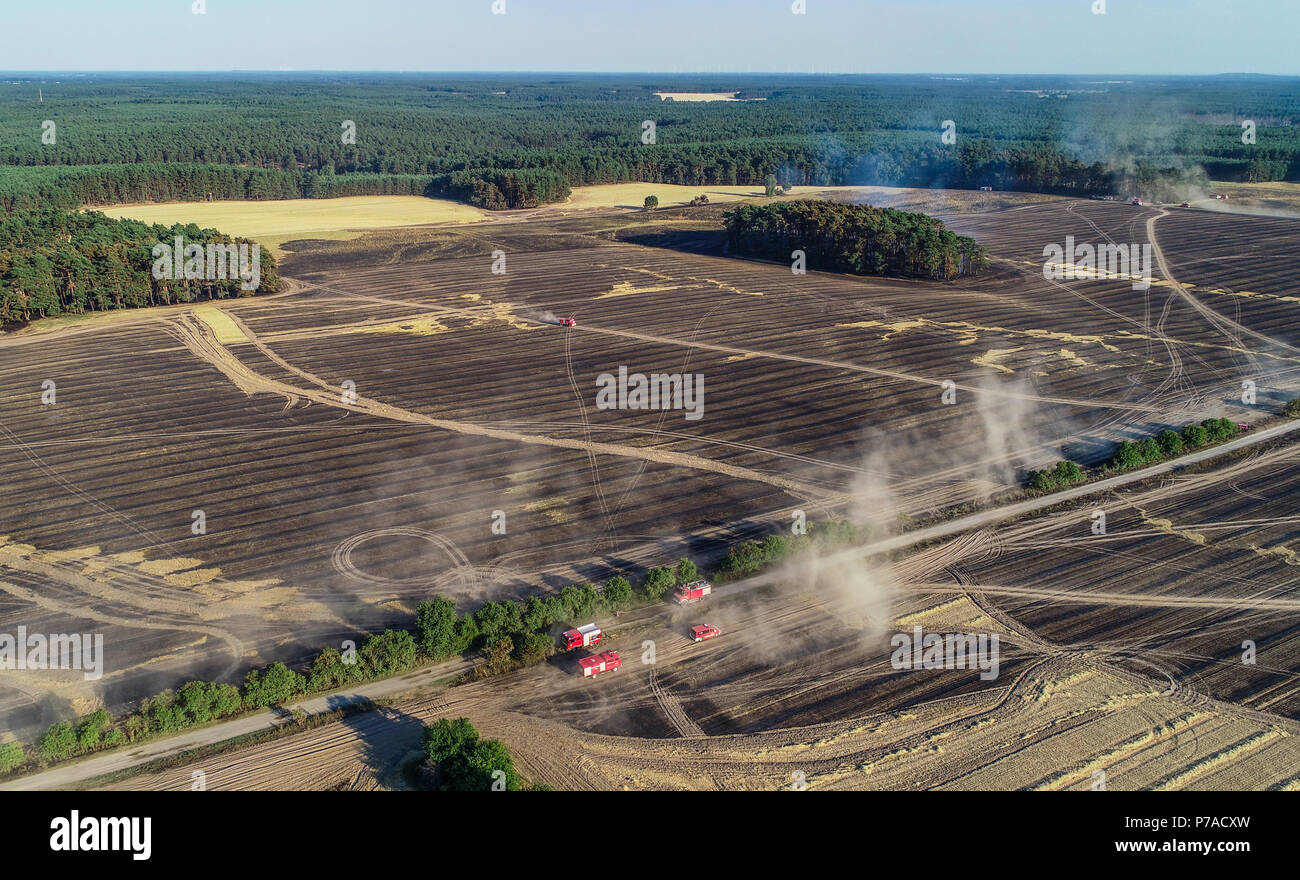 Germany, Limsdorf. 4th July, 2018. Fire department cars drive over a burned-out field. The fire which caught on some 100 hectars of forest and field land was put out over night on Thursday. More than 13 hours were needed to quench the fire in the district of Limsdorf, as the fire department reported. The police is yet unable to provide a source for the fire outbreak. Brandenburg is currently at its highest risk for forest fires. Credit: Patrick Pleul/dpa-Zentralbild/dpa/Alamy Live News Stock Photo