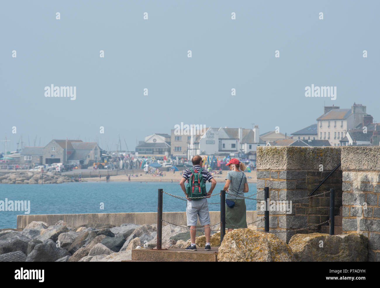 Lyme Regis, Dorset, UK. 5th July 2018. UK Weather: Hot with hazy sunshine in Lyme Regis. Visitors and locals head to the beach at the coastal resort of Lyme Regis. The outlook is good with high pressure dominant brigning hot conditions and humidity over the weekend. Credit: Celia McMahon/Alamy Live News Stock Photo