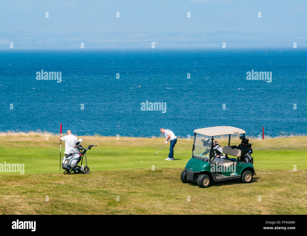 North Berwick, East Lothian, Scotland, United Kingdom, 5th July 2018.  Golfers with a golf buggy playing on Glen Golf Course beside the Firth of Forth Stock Photo