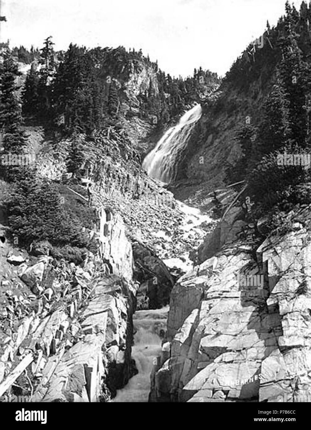 . English: Sluiskin Falls, Mount Rainier National Park, Washington, ca. 1910. English: Man with alpenstock standing to the left of the waterfall . On sleeve of negative: Mt. Tacoma. Paradise. Canyon view of Sluiskin Falls. Subjects (LCTGM): Waterfalls--Washington (State)--Mount Rainier National Park; Canyons--Washington (State)--Mount Rainier National Park Subjects (LCSH): Sluiskin Falls (Wash.); Mount Rainier National Park (Wash.)  . circa 1910 76 Sluiskin Falls, Mount Rainier National Park, Washington, ca 1910 (BAR 235) Stock Photo
