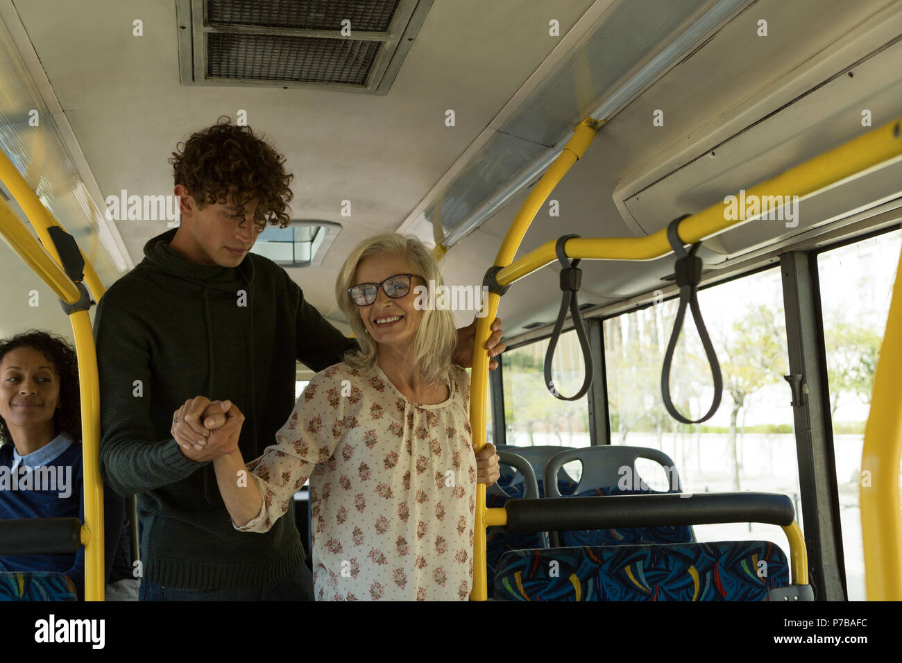 Young man helping senior woman in the bus Stock Photo