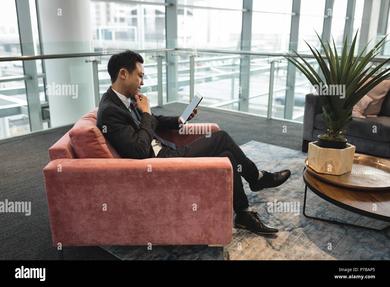 Businessman sitting on chair and using tablet Stock Photo