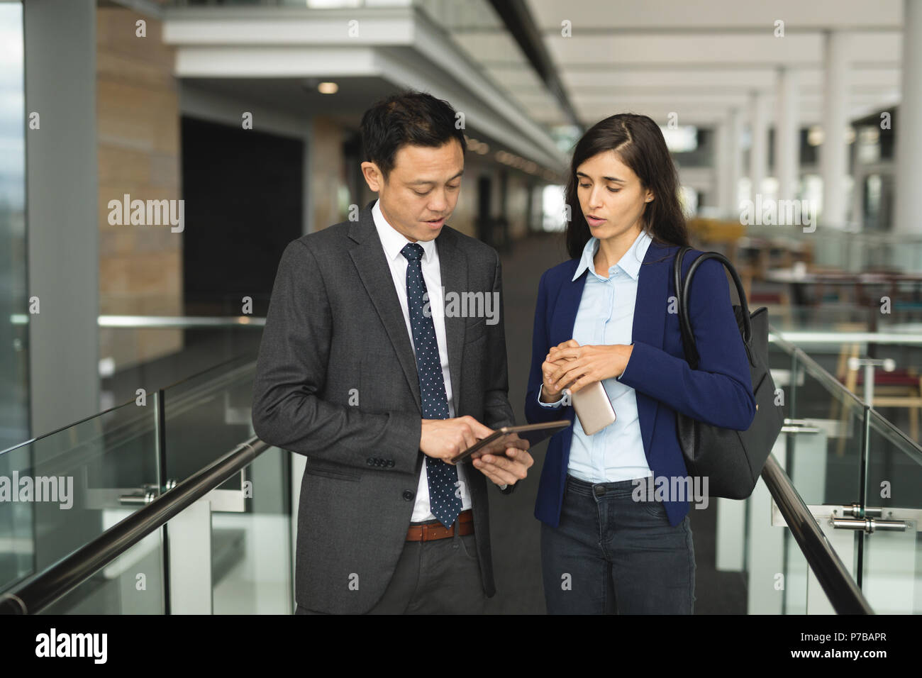 Businessman and businesswoman discussing over a digital tablet Stock Photo