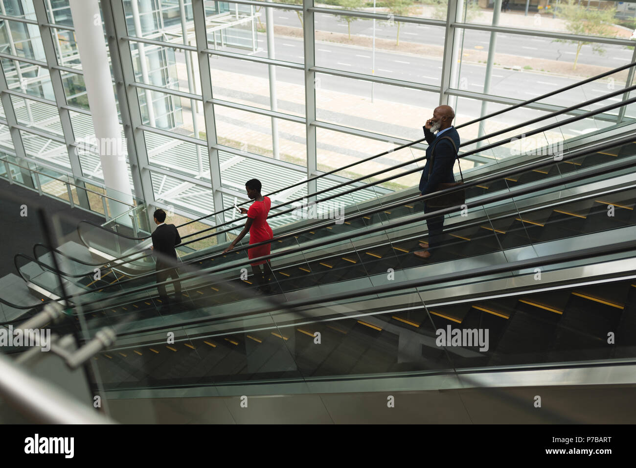 Businesspeople going down on an escalator in the office Stock Photo
