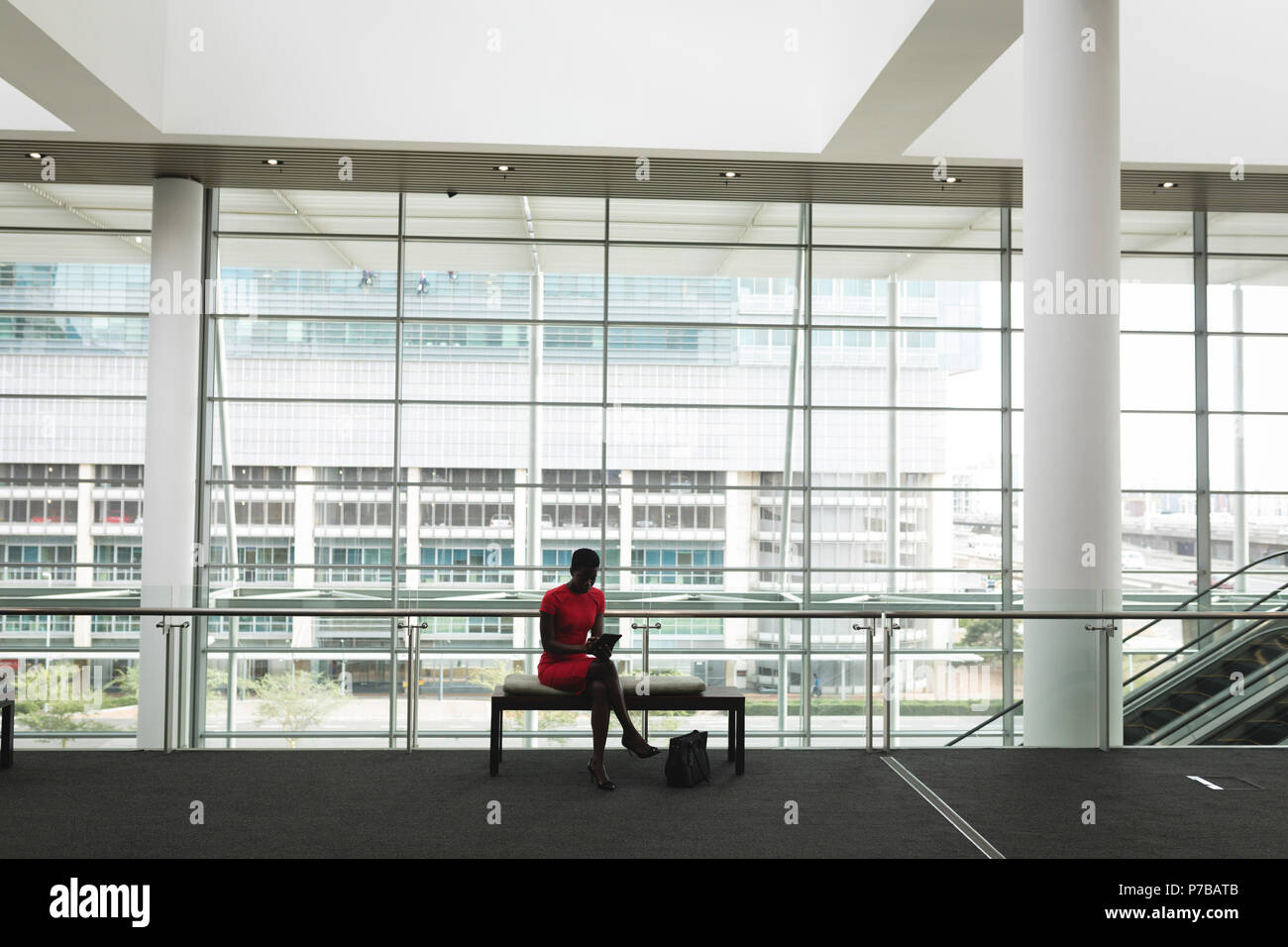 Businesswoman sitting on a bench and using tablet Stock Photo