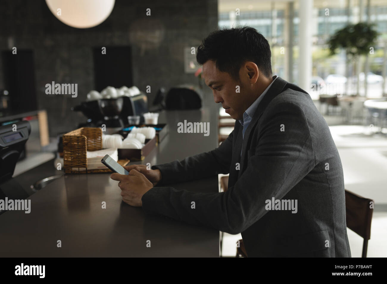 Businessman using his phone at the cafeteria counter Stock Photo