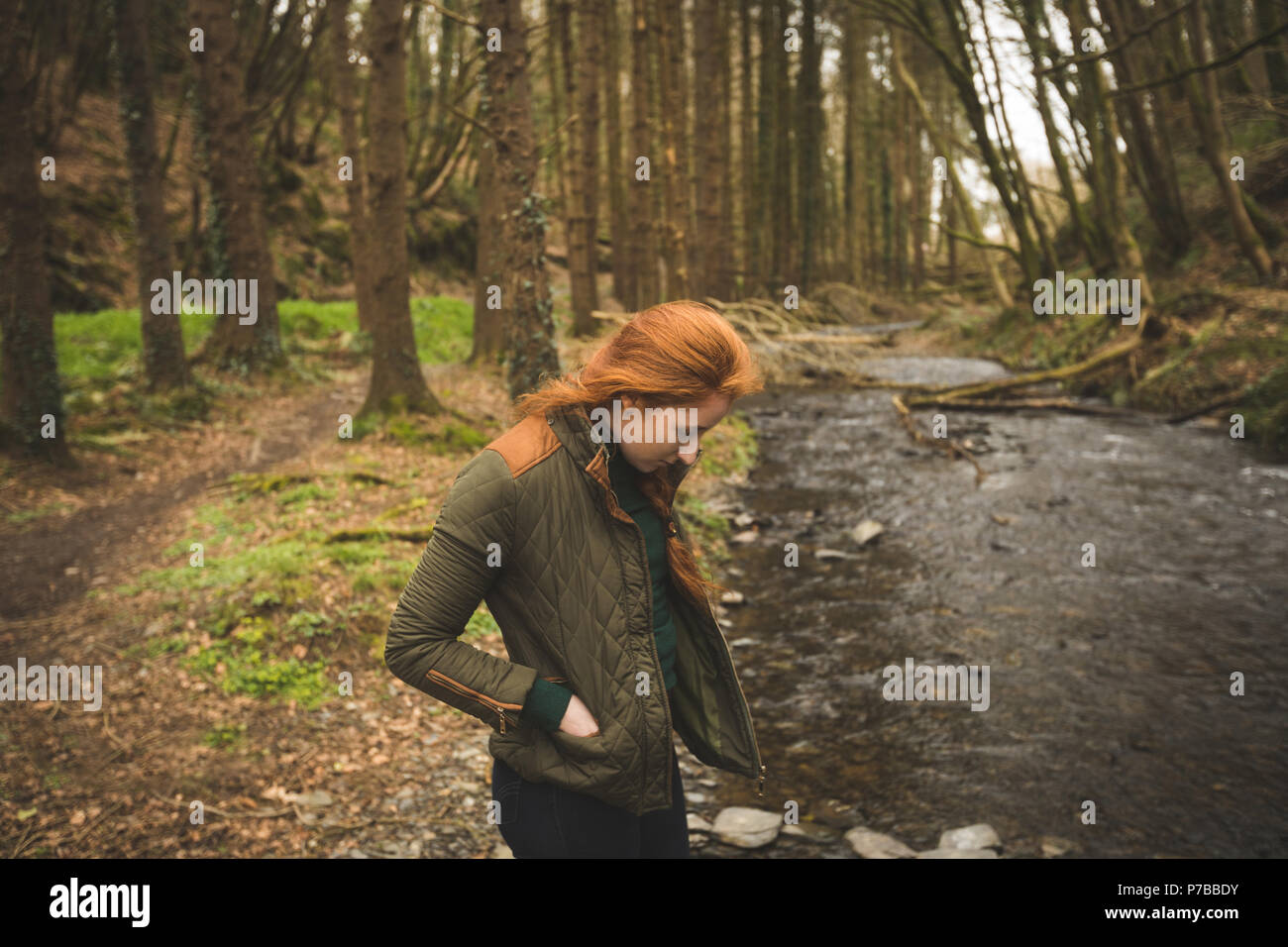 Female hiker looking at the shallow river in the forest Stock Photo