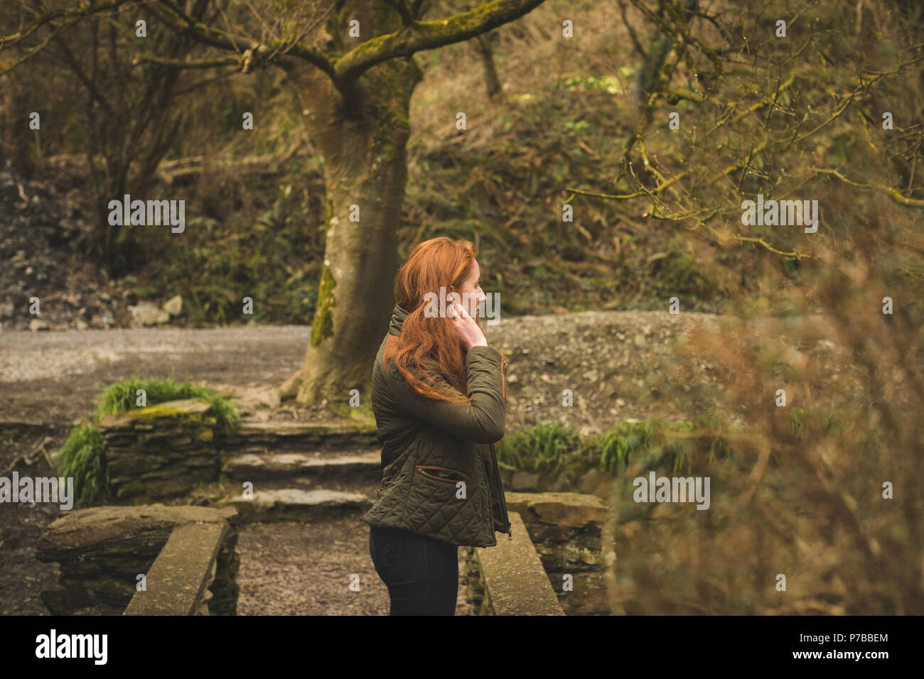Red hair female hiker looking around in the forest Stock Photo