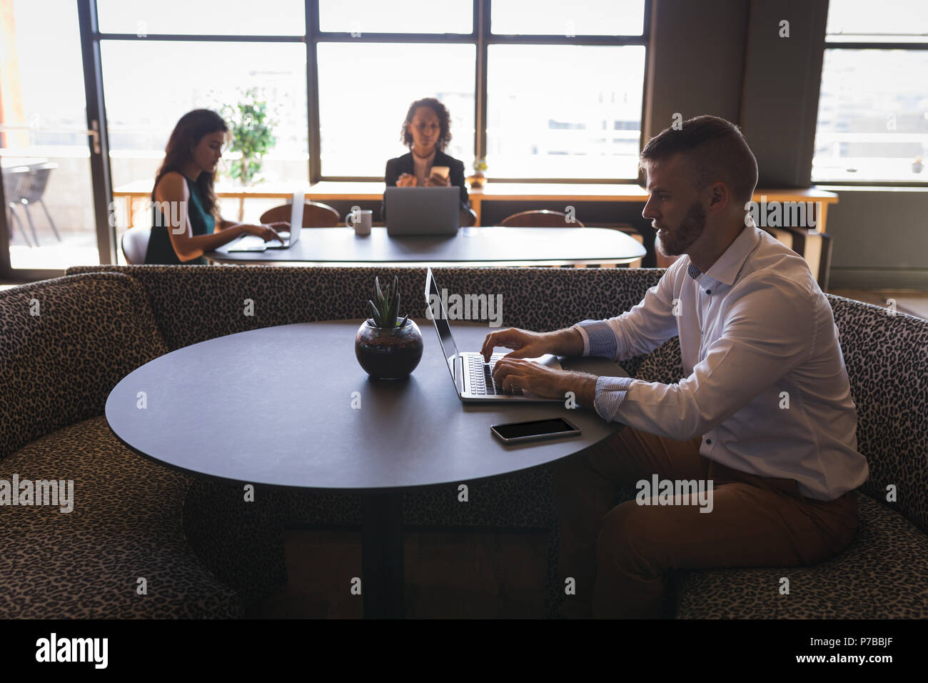 Business executives sitting and working on laptop in cafeteria Stock Photo