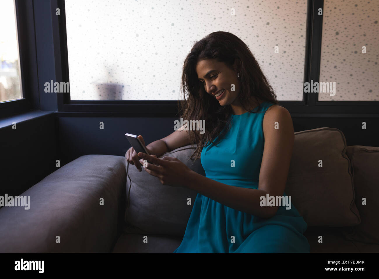 Businesswoman using smartphone while sitting on sofa at office Stock Photo