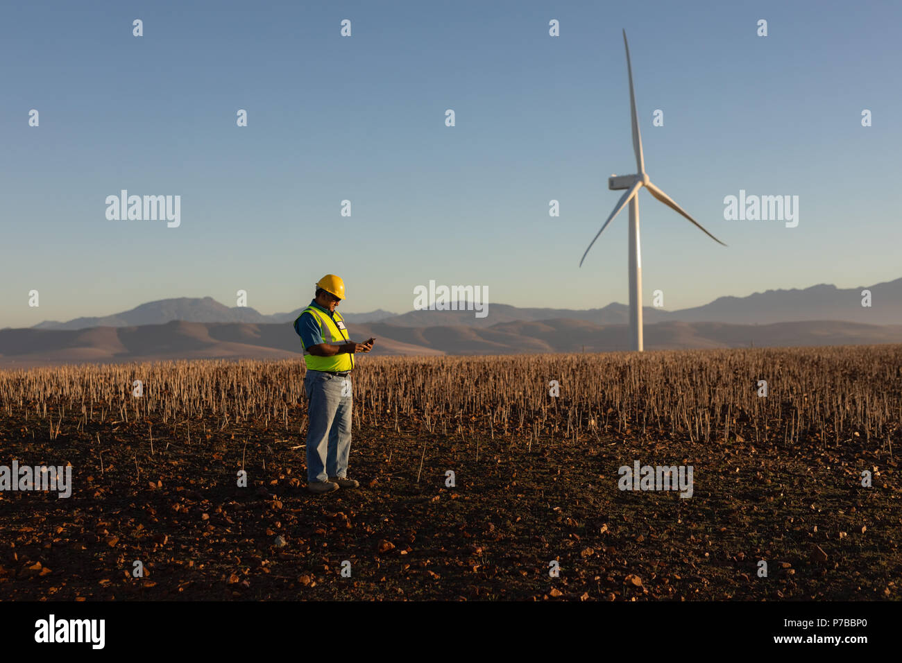 Engineer using mobile phone at wind farm Stock Photo