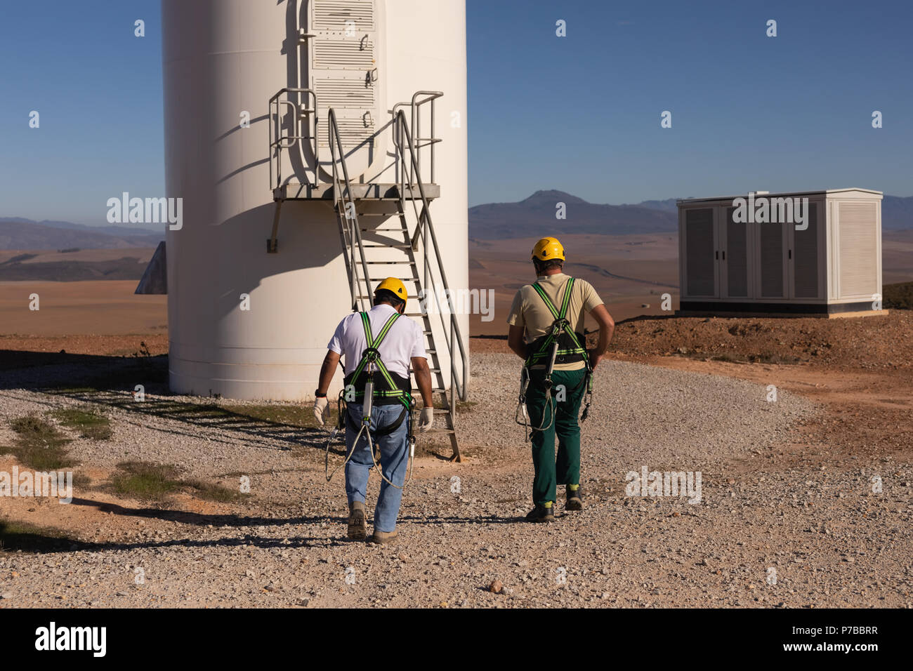 Engineers walking toward a wind mill at a wind farm Stock Photo