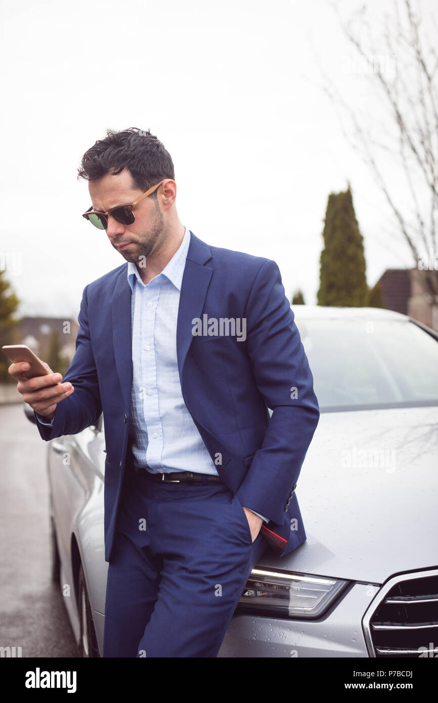 Businessman using mobile phone near a car Stock Photo