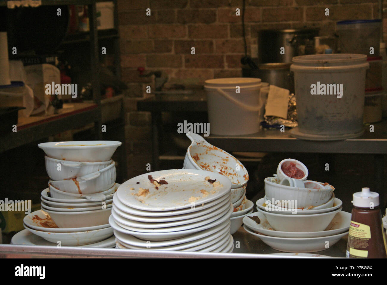 DIRTY DISHES STACKED AND READY FOR WASHING IN A SMALL CAFE IN SYDNEY, AUSTRALIA Stock Photo