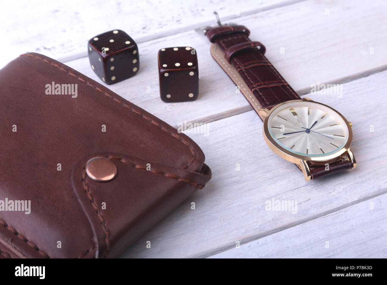 Men's accessories for business and rekreation. Watch, leather wallet and dice on wood background.. Top view composition. Stock Photo