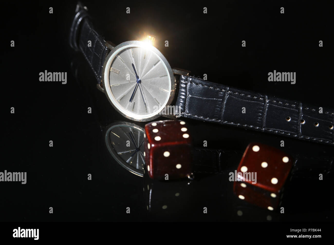 Men's accessories for business and rekreation. Watch and dice on black mirror background.. Top view composition. Stock Photo