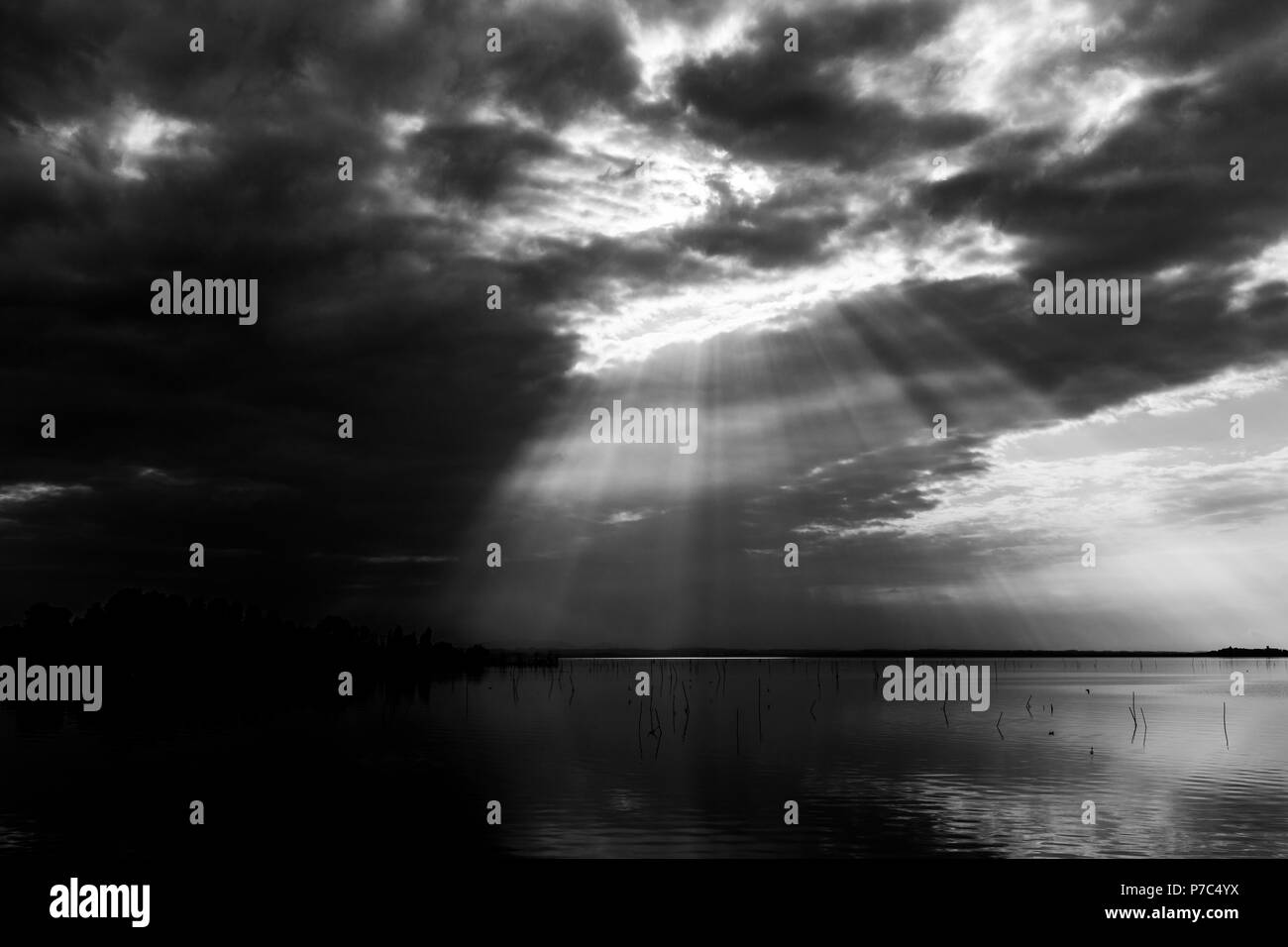 Perfectly symmetric and spectacular view of a lake, with clouds, sky and sun rays reflecting on water Stock Photo