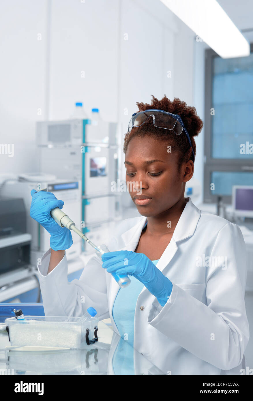 Africanamerican scientist or graduate student in lab coat and protective wear works in modernl