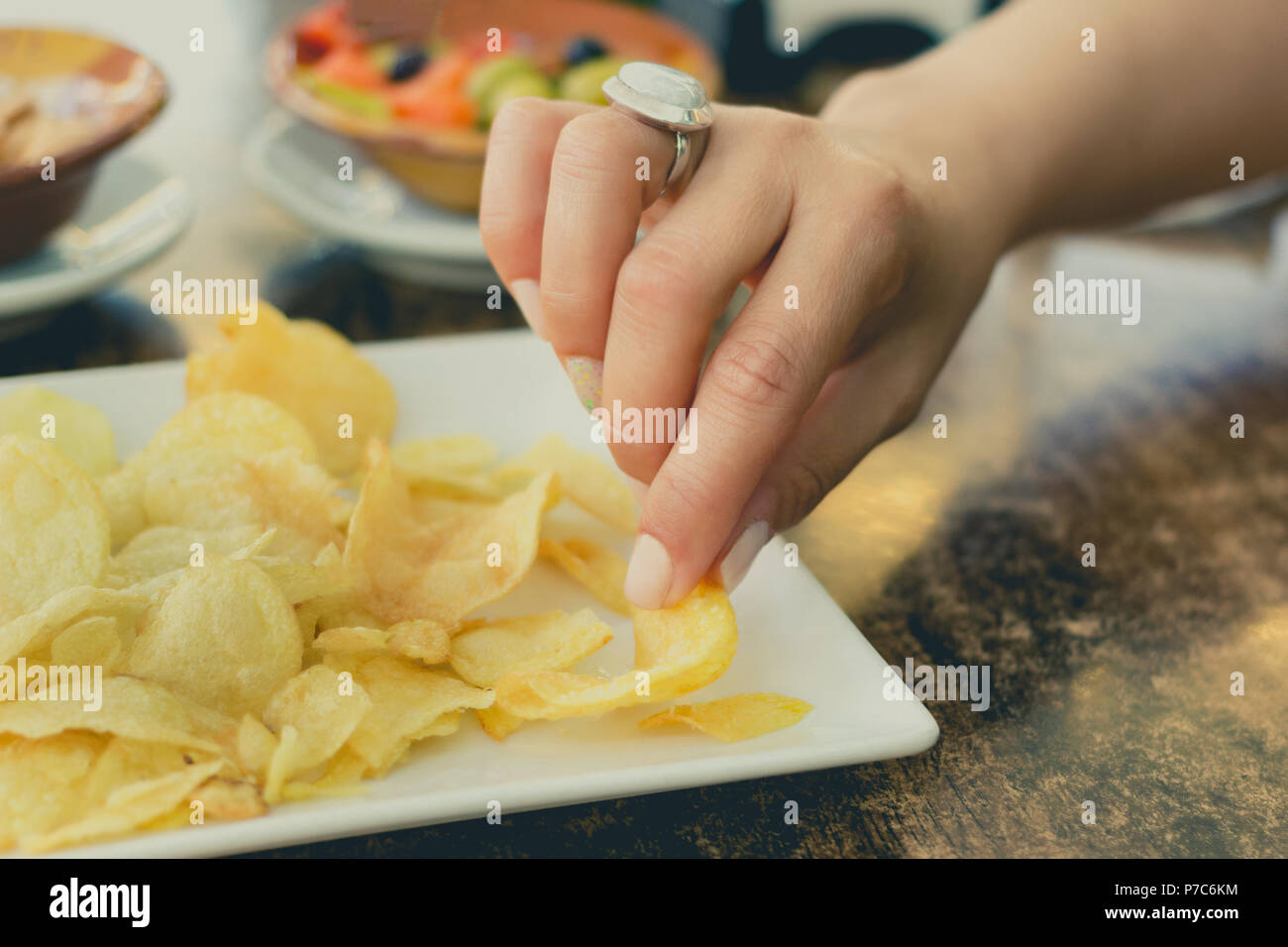 Hands of a woman picking a fried potato during a snack Stock Photo