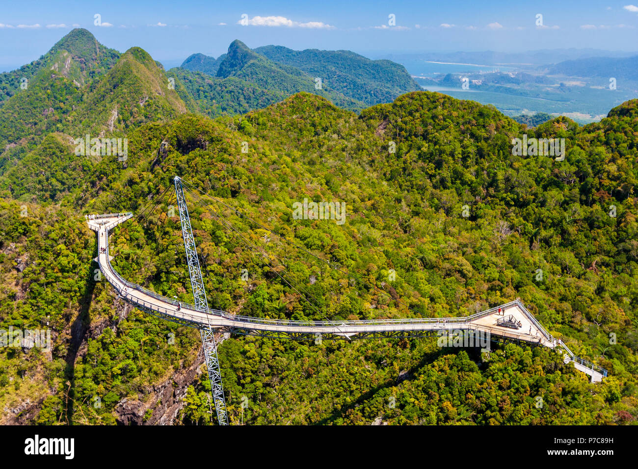 Aerial perspective of the Langkawi Sky Bridge, a curved pedestrian cable-stayed bridge with triangular viewing platforms, connecting two hilltops at... Stock Photo