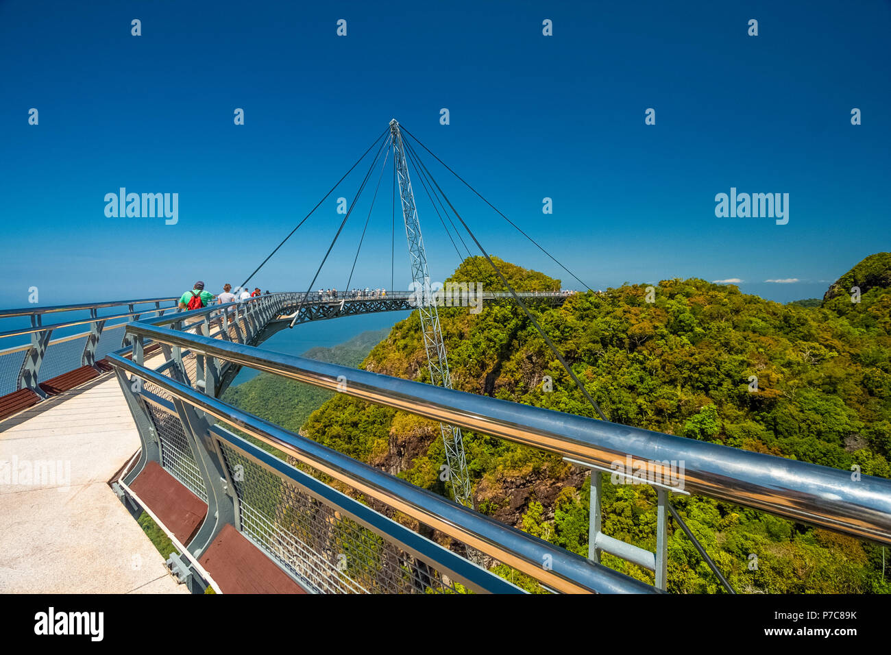Tourists walking on the Langkawi Sky Bridge, a curved pedestrian cable-stayed bridge, suspended by cables from a single pylon, at the peak of... Stock Photo