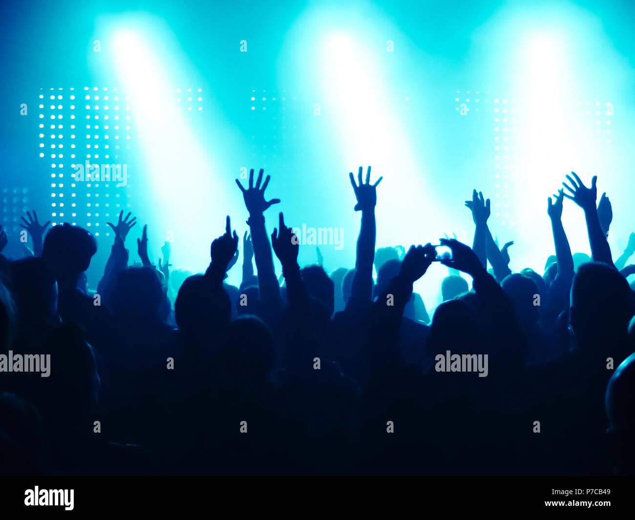cheering crowd at rock concert in front of bright lights Stock Photo