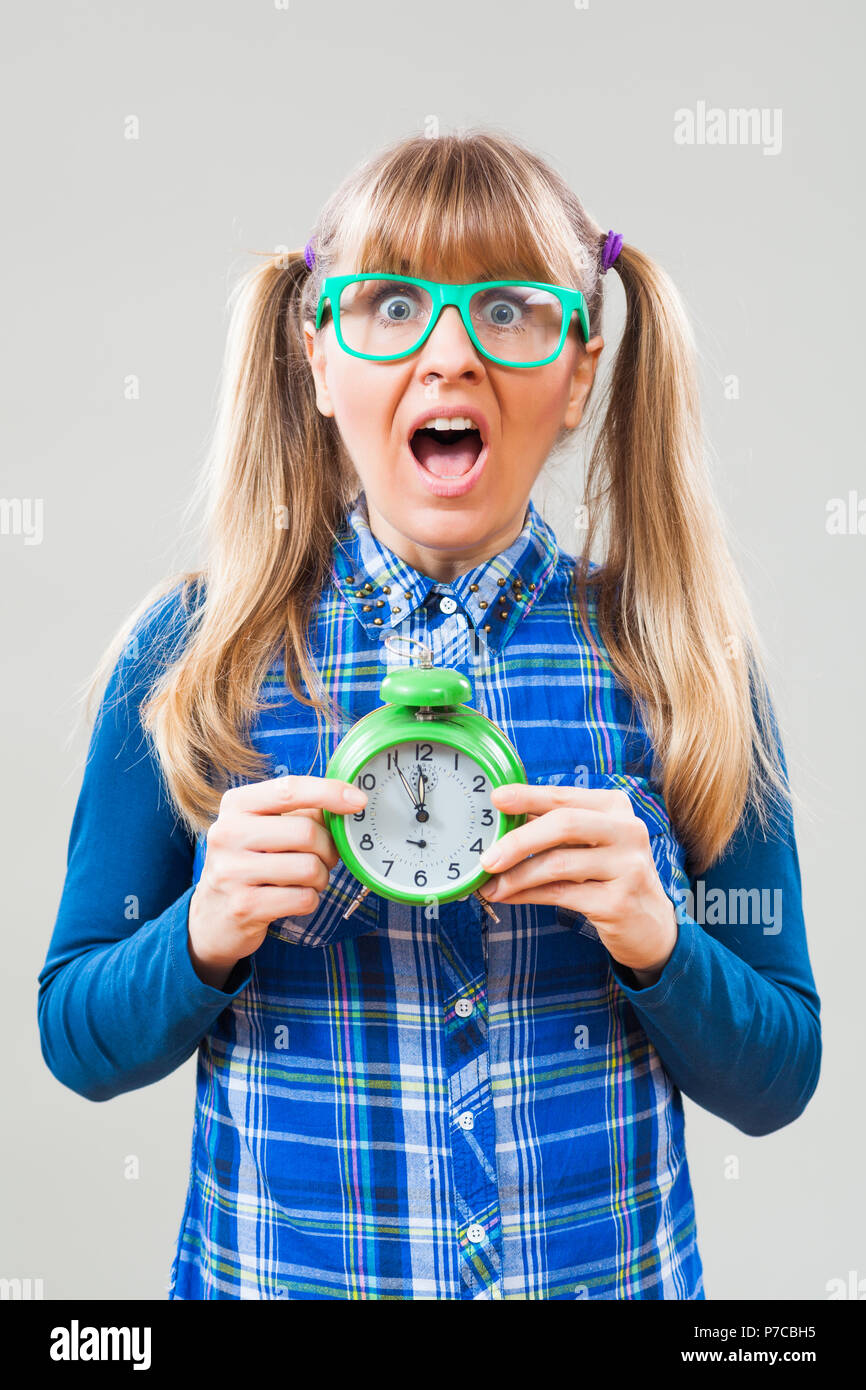 Studio shot portrait of nerdy woman who is holding clock that shows
