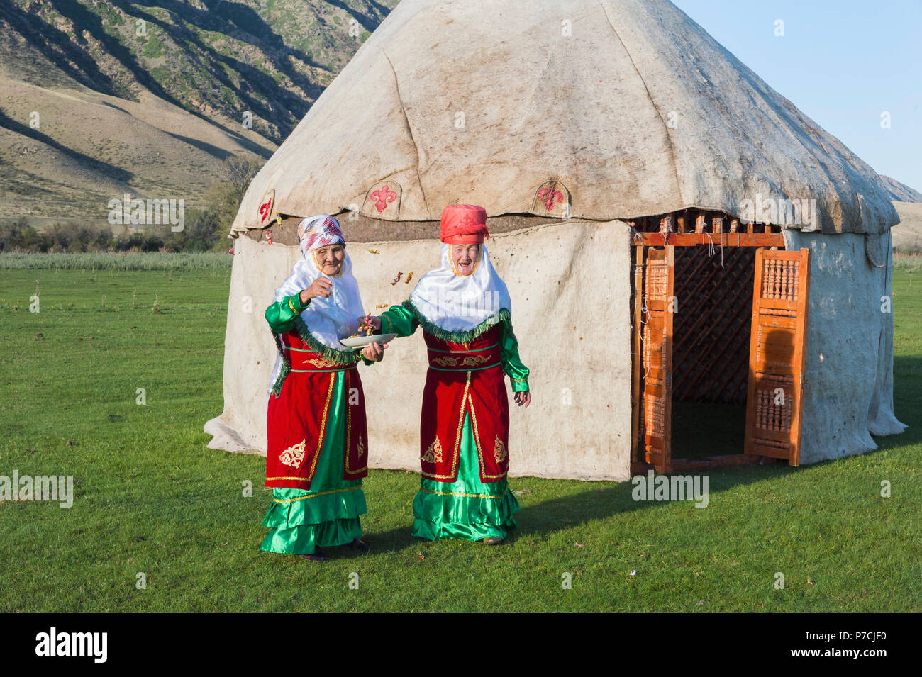 Two Kazakh women in traditional clothes, in front of  yurt, welcoming guests, For editorial Use only, Sati village, Tien Shan Mountains, Kazakhstan Stock Photo