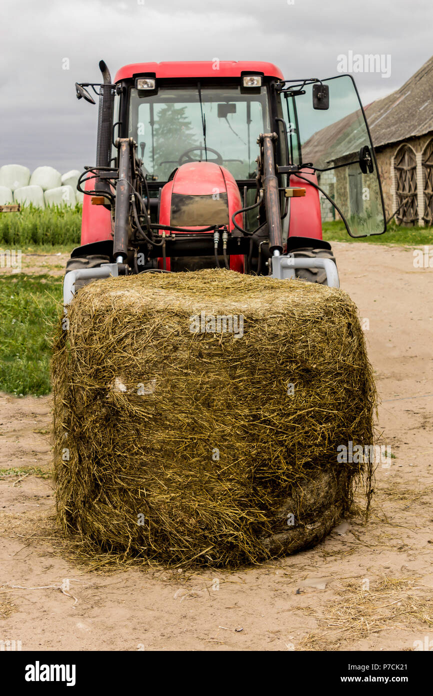 Unpacked from the membrane a silage bale and a tractor with a forklift