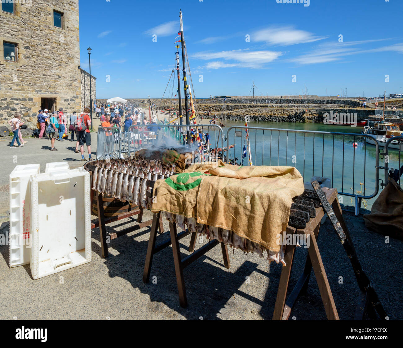 PORTSOY FESTIVAL ABERDEENSHIRE SCOTLAND ARBROATH SMOKIES HADDOCK FISH ON RACKS WAITING TO BE SMOKED WITH BARREL COVERED WITH  SACKS SMOKING SOME FISH Stock Photo