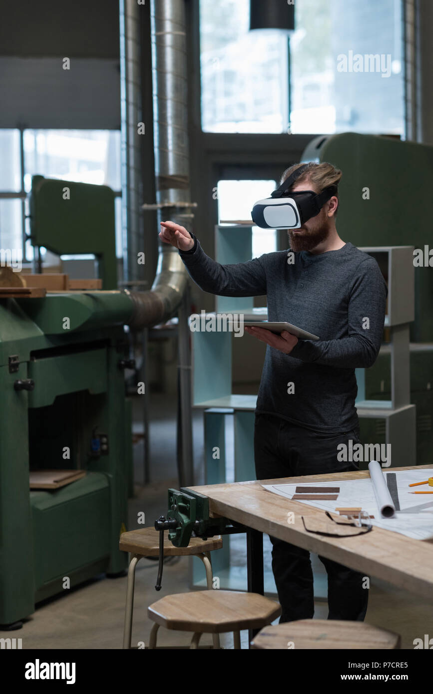 Male carpenter with digital tablet using virtual reality headset Stock Photo