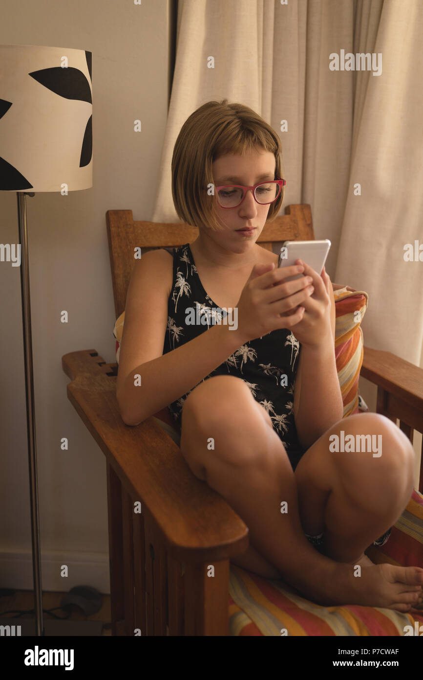 Girl using mobile phone in living room Stock Photo