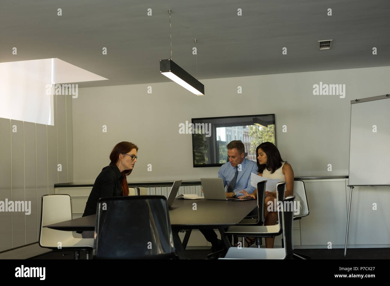 Business colleagues working on laptop in conference room Stock Photo