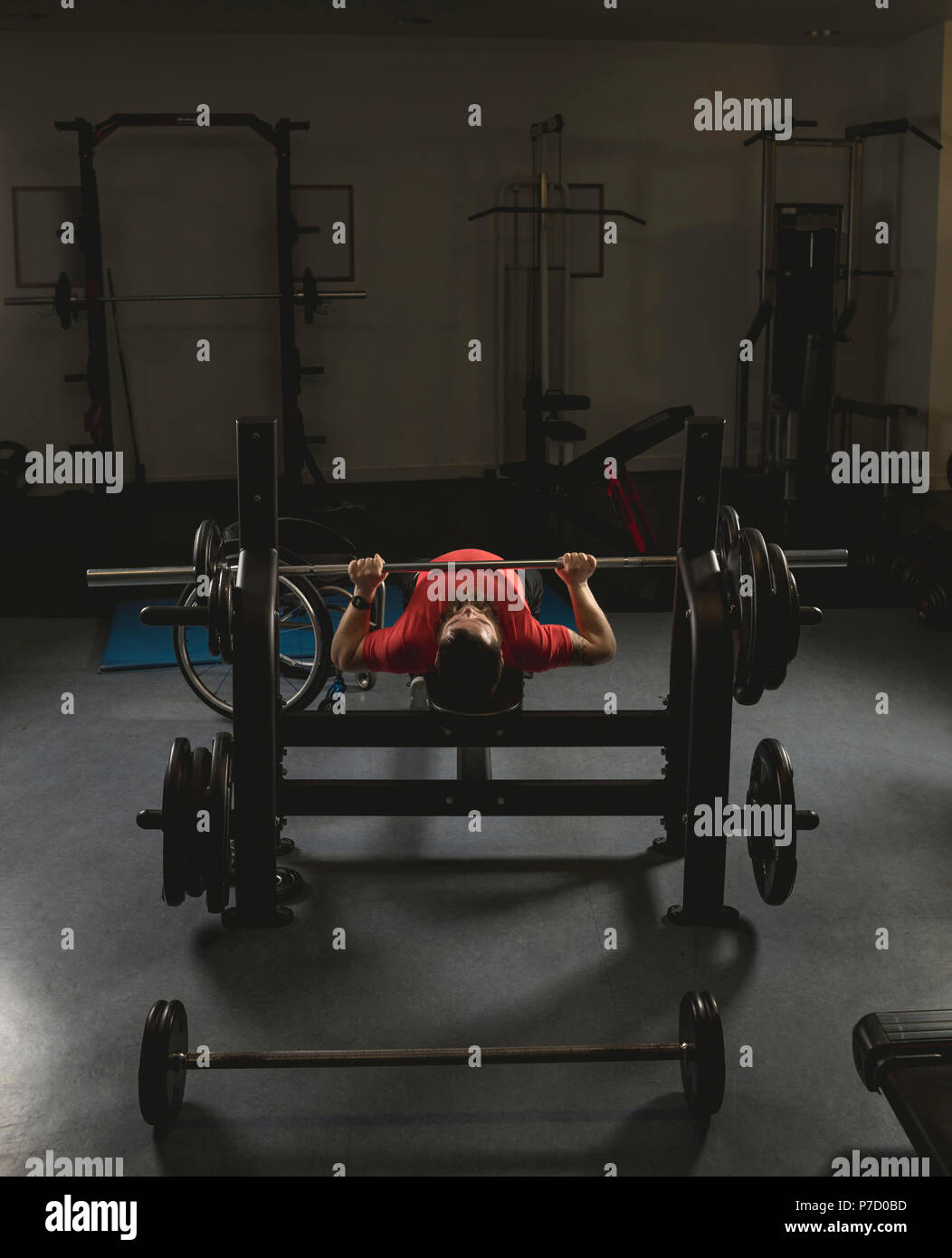 Handicapped man doing barbell bench pressing while exercising Stock Photo