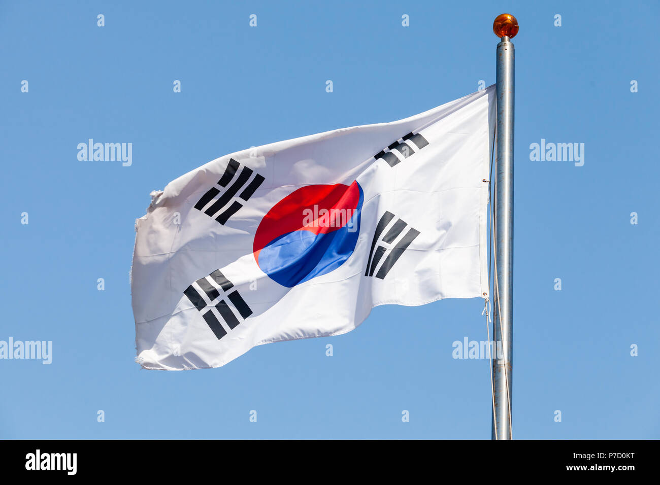Flag of South Korea, also known as the Taegukgi waving on a flagpole over blue sky background Stock Photo