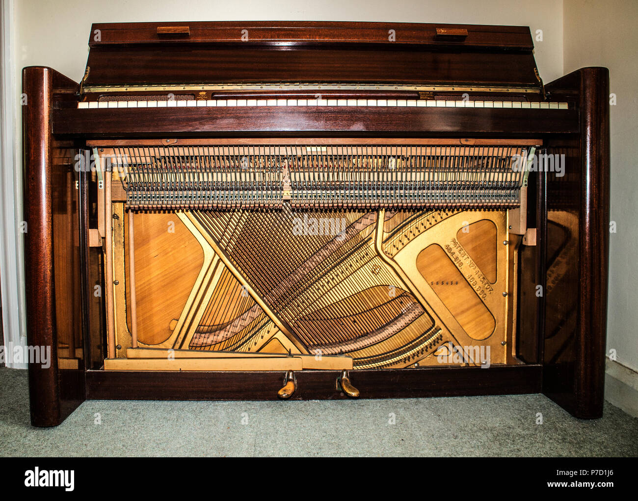 View of soundboard,wires and mechanism (front panel removed) of a 1950s dark mahogany Eavestaff  Pianette 'Minipiano'. Stock Photo