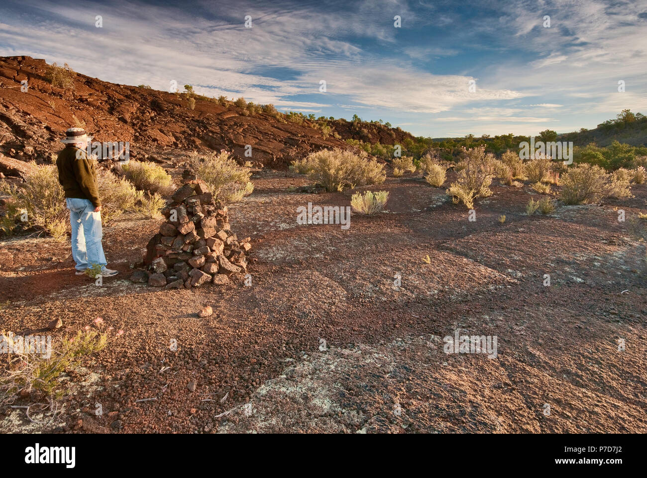 Hiker at volcanic rock cairn at sunrise in Lava Falls Area, El Malpais National Monument, New Mexico, USA Stock Photo