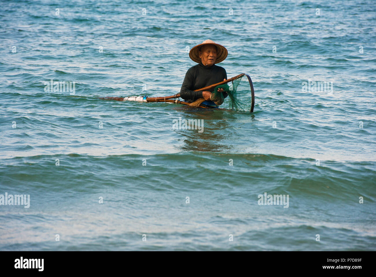 Mussel hunter, shellfish fisherman wearing a straw hat, Cua Dai beach in Hoi An, Vietnam Stock Photo